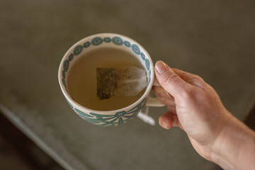 Senior woman's hand holding a cup of tea.
