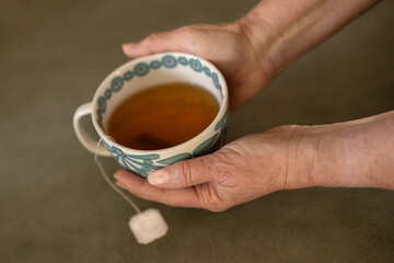 Senior woman's hands holding a cup of tea.