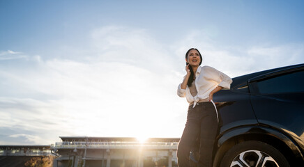 Young beautiful asian women buying new car. she was standing near car on the roadside. Beautiful moment blue sky Smiling female driving travel by vehicle on the road on a bright day with sun light. - obrazy, fototapety, plakaty