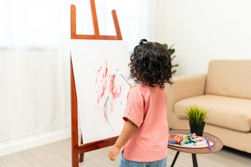 Happy moment little cute girl creating and water color painting activity with paint brushes on...