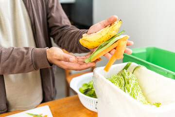 Ecology compost supply Kitchen waste recycling composter environmentally friendly. The young man throws leftover fruit peel and vegetables reduce waste