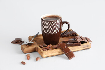 Wooden tray with cup of tasty hot chocolate, spoon and cocoa beans on white background