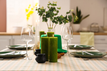 Festive table serving with leprechaun's hat and burning candles in dining room. St. Patrick's Day celebration