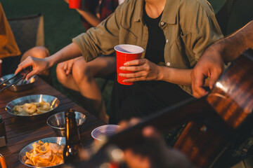 Cheers! Group of asian people friend party camping in nature making toasting with soft drink and beer red cup. Hangout party outdoor in campsite nature forest background on holiday weekend vacation - obrazy, fototapety, plakaty