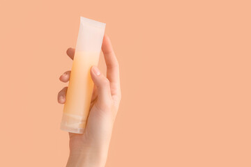 Female hand with tube of natural cream on color background, closeup