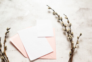 Spring Easter composition. Blank white greeting card with pink envelope and spring willow branches. Neutral colors.