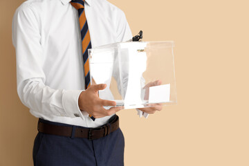 Man holding ballot box on beige background. Election concept