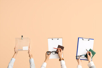 Hands holding ballot box, passports and clipboards with voting papers on beige background. Election...
