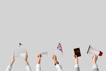 Hands holding ballot box, UK flag, passport and megaphone on white background. Election concept