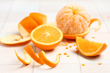 Composition with fresh ripe oranges and peel on light tile background