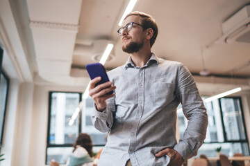 Young businessman browsing smartphone in modern workspace
