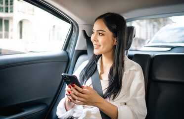Asian Woman Traveler sitting in car back seats using smartphone call taxi service in application. Online app with cell phone and put on safety belt. Female passenger in car traveling to destination.