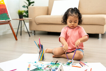 Happy moment little cute girl creating and water color painting activity with paint brushes on...