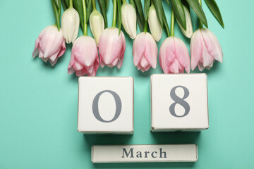 Tulip flowers and wooden calendar on turquoise background. International Women's Day celebration