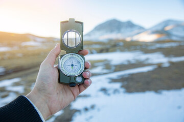 hand holding compass in winter mountains background