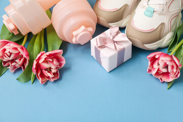 Dumbbells, shoes, gift and tulip flowers for International Women's Day on color background