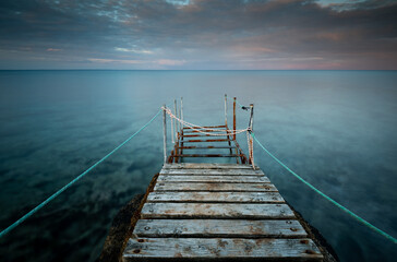 Long wooden pier in the sea at sunset.