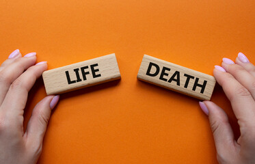 Life or Death symbol. Concept word Life or Death on wooden blocks. Businessman hand. Beautiful...