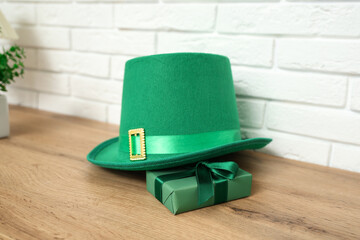 Leprechaun's hat and gift box on table in living room, closeup. St. Patrick's Day celebration