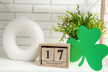 White shelf with paper clover leaf, cube calendar and decor in living room, closeup. St. Patrick's...