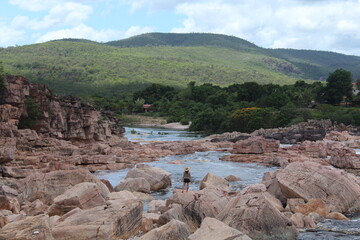 mulher caminhando em pedras no Rio Paraguaçu em Andaraí, na Chapada Diamantina, Bahia