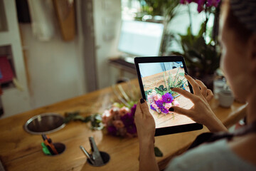 Florist taking picture of bouquet on tablet in flower store