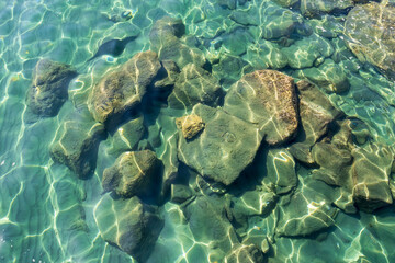 Rocks under gleaming transparent aquamarine sea water  