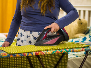 girl ironing clothes with an iron on an ironing board