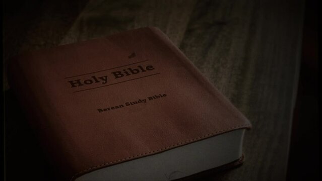 Holy Bible Sacred Book On Table Old Film Texture Zoom In. Tracking shot of a holy bible sacred book left on a table. Tracking shot