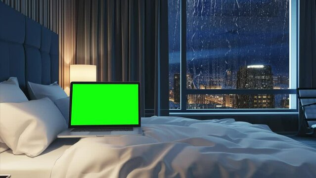Laptop with replaceable chroma key screen in apartment bedroom before wide window with rainy cityscape, looped footage