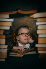 A girl is reading a book on the background of a stack of books