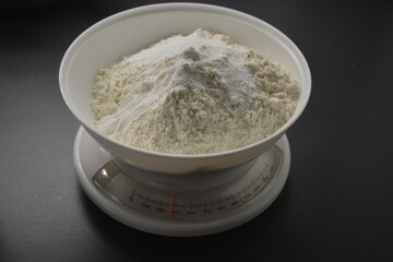 Homemade, tabletop, white weights with wheat flour are located on the gray countertop of the kitchen.