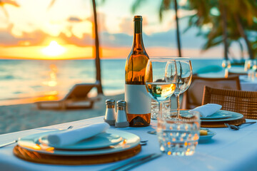 Romantic dinner table in the beach. Two glasses and a bottle of wine with the sunset view. Concept of spring and summer activities