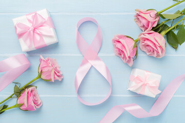 Composition with pink roses, gift box and eight made of ribbon on wooden background, top view. Women's day concept