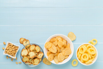 Various unhealthy snacks on wooden background, top view