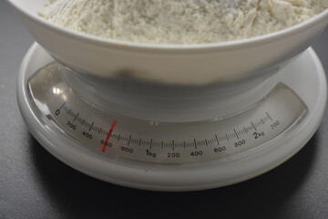 Homemade, tabletop, white weights with wheat flour are located on the gray countertop of the kitchen.
