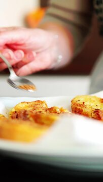 Mujer mayor irreconocible espolvoreando az&uacute;car panela sobre el pan para la receta de torrijas de Semana Santa.