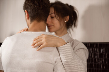 female feels protected behind his strong back. woman trustingly hugs her lover's neck.