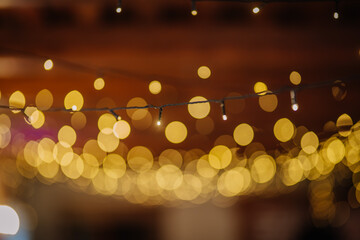 Valmiera, Latvia - July 7, 2023 - Focused string lights with blurred golden bokeh effect against a...