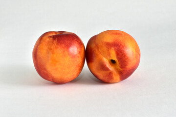 Two juicy, tasty, vitamin-rich nectarine fruits lie on a white background.