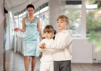 Obraz premium Boy with pair girl in sport wear train to dance vigorous hustle during classes. Children rehearse contemporary dancing movement. Female teacher conducts class for students