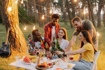 Group of multiracial friends having fun at party, drinking beer and making toast