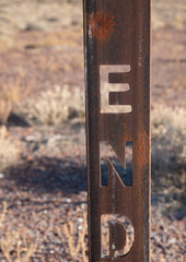 End sign in desert on rusted metal post.  Marks end of a road.  