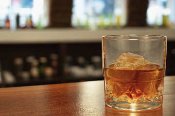 A glass of whiskey with ice. Background with copy space. A glass of alcohol on the bar counter
