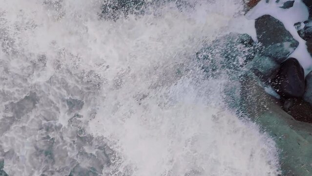 Aerial: Waves crashing over boulders in slow motion. Oamaru, Otago, New Zealand.