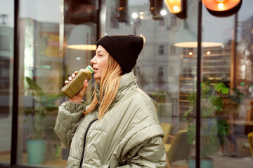 Young hipster girl with green vegetable smoothie drink outdoor.