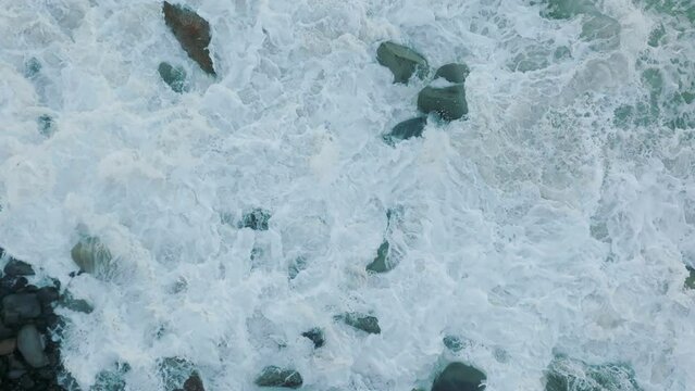 Aerial: Waves crashing over boulders in slow motion. Oamaru, Otago, New Zealand.