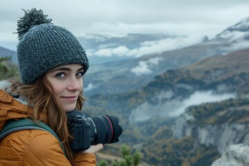 Fototapeta na wymiar A girl, photographer is enjoying the view from a top of a mountain and holding a camera