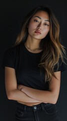 Attractive young Asian woman in simple black t-shirt, silver necklace, and jeans with arms crossed