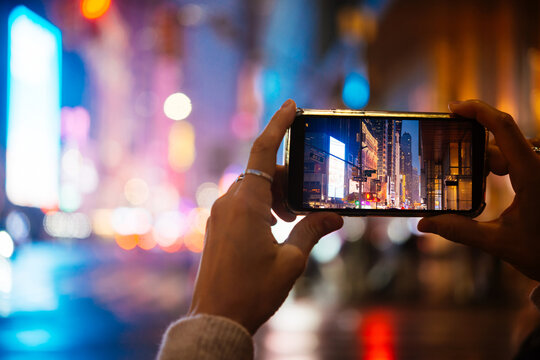 A person takes a mobile photo of evening Manhattan lights in New York City, United States.